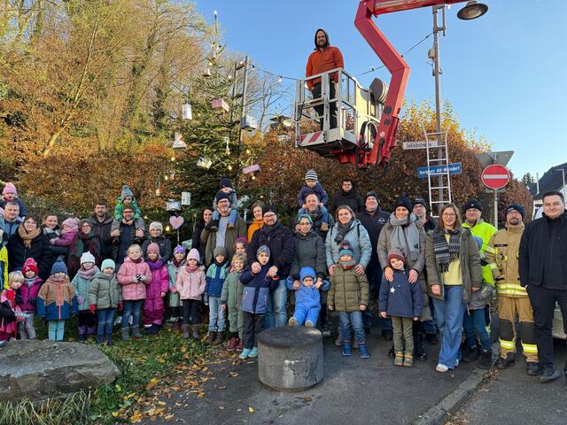 Gemeinsam geschmückt: Die Kinder der KiTa „Pauline“ mit ihren Eltern sowie der Abordnung der Wolsdorfer Löschgruppe III und den bewirtenden Junggesellen der „Eintracht“ vor dem Dorf-Weihnachtsbaum von Alt-Wolsdorf.  | Foto: JGV