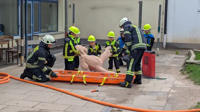 Der verletzte Bär wird vom jungen „Feuerwehrteam“ vorsichtig auf die Trage gehoben.  | Foto: Feuerwehr Hunstig