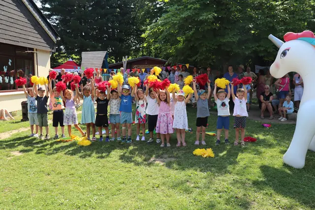 Das Einhorn schaut zu, als die Kinder mit roten und gelben Puscheln ihren Tanz aufführen.  | Foto: AWO Rhein-Oberberg/Sabine Eisenhauer