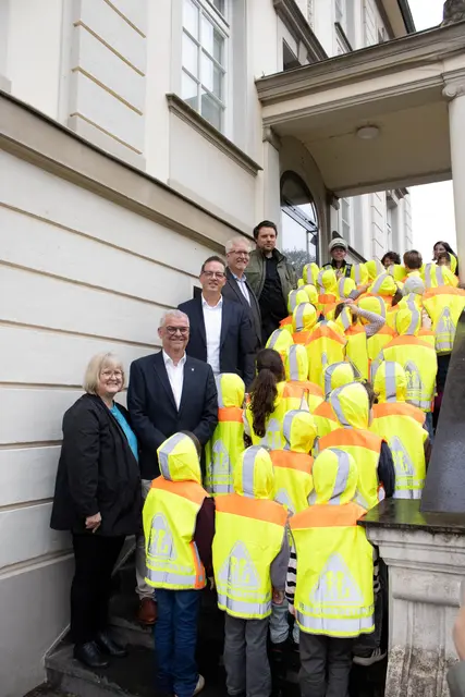 Ein leuchtendes Zeichen für mehr Sichtbarkeit: Die Erstklässler der Katholischen Grundschule Brühl-Pingsdorf nahmen ihre neuen Sicherheitswarnwesten entgegen. Begleitet wurde die Übergabe von Rektorin Jutta Pohl, Bürgermeister Dr. Marc Prokop, Gregor Golland, Stefan Grathwohl von der Kreissparkasse Köln, Mobilitätsmanager Alexandre Ludwig und Mirko Laszig von der Polizei. | Foto: REVG