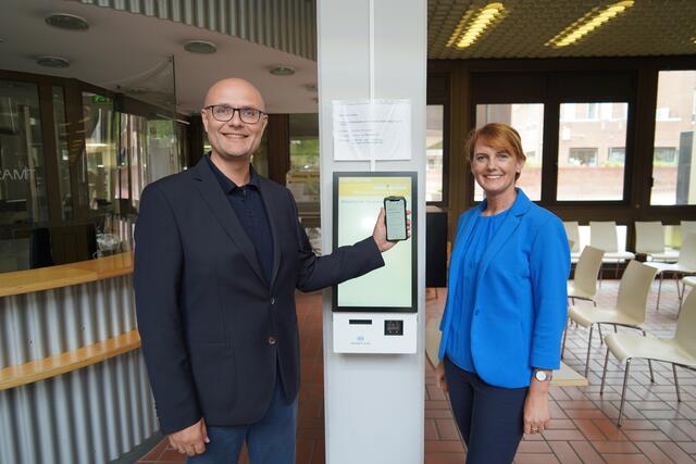 Gudrun van Cleef (r.) und Norbert Sester vor dem Bondrucker des Bürgeramts mit Smartphone.  | Foto: Stadt Frechen