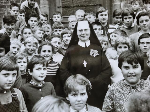 Unter Strempter Kindern: „Tante Billa“, alias Schwester Clematia, 1961 auf Heimaturlaub in der Eifel. Der Kirchenchor sang, die Musik spielte.  | Foto: Foto/Repro/Manfred Lang/pp/Agentur ProfiPress