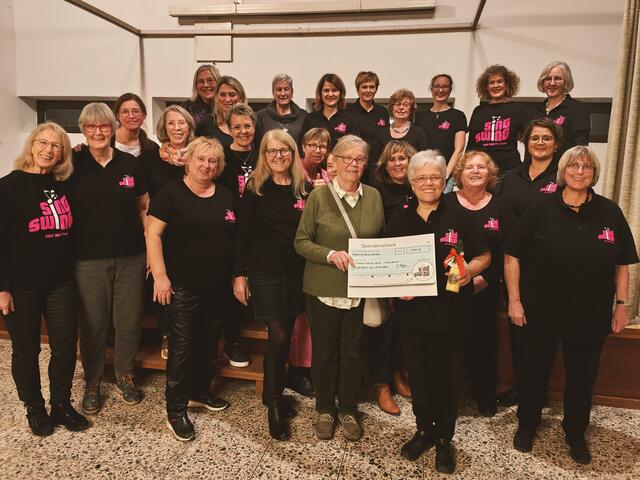 Dagmar Bürger von Sing Swing übergibt den Spendenscheck im Beisein des Chores an Barbara Hasberg von „Tischlein-Deck-Dich“.  | Foto: Chor