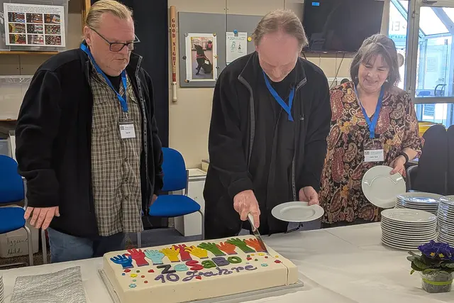Zur Feier des Tages gab es eine Torte, die die ehrenamtlichen Mitareiter Paul, Peewee und Uschi (v. l.) angeschnitten haben.  | Foto: fes