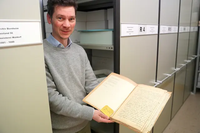 Ein Blick ins schriftliche Gedächtnis der Stadt: Stadtarchivar Dr. Simon Oelgemöller zeigt eine historische Akte, die im Rahmen einer Trockenreinigung von Staub und schädlichen Rückständen befreit wurde. | Foto: Stadt Bornheim