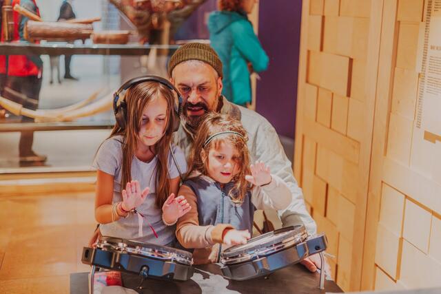 Ein Vater und seine zwei Töchter an der Mitmchstation Drum Battle in der MUSIC-Ausstellung.  | Foto: Katja Velmans/LVR-LandesMuseum Bonn