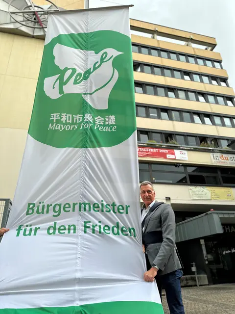 Zum Flaggentag am 08. Juli hisst Bürgermeister Ralph Manzke vor dem Neuen Rathaus die Flagge der Mayors for peace. Wesseling ist seit 2023 Mitglied des Netzwerks.  | Foto: Stadt Wesseling