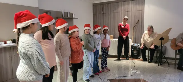 Mit Nikolausmützen standen Kinder aus dem „Haus International“ bei der Adventsfeier im Herman-Josef-Lascheid-Haus auf der „Bühne“ und sangen für die älteren Zuhörer.  | Foto: Stadt Troisdorf
