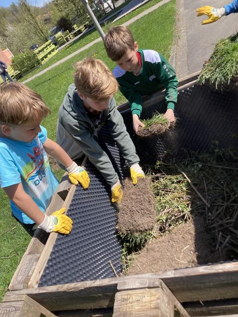 Eine Lage im Hochbeet: Vorsichtig schichten die Kinder Grassoden ins „Palettenbeet“.