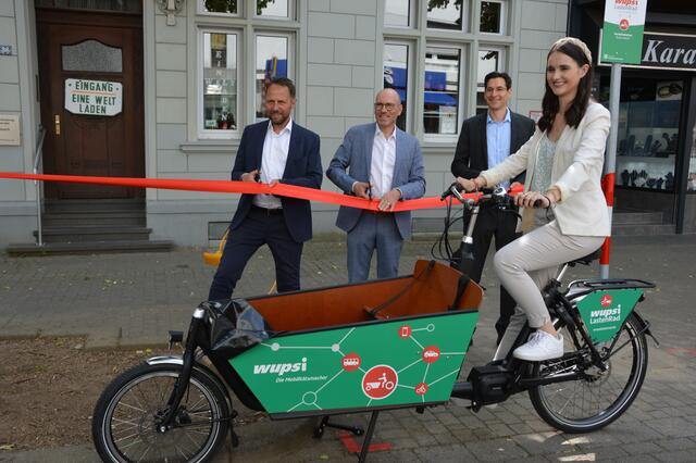 Das rote Band schnitten durch:  OB Uwe Richrath, Wupsi-Chef Marc Kretkowski und Dr. Ernst Raupach, Geschäftsführer Green Moves (von links) Wupsi-Mitarbeiterin Tanja Schmitz testete das E-Lastenrad.  ,  | Foto: Ursula Willumat
