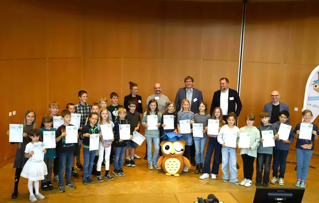 Kinderuni-Diplomfeier 2025 an der H-BRS: Gruppenbild mit Organisatorin, Dozierenden und dem Kinderuni-Maskottchen, der Eule Cosma.  | Foto: Juri Küstenmacher/H-BRS