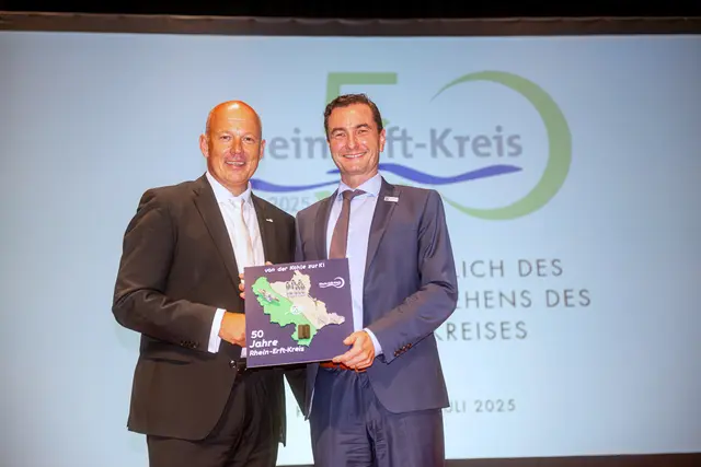 Landrat Frank Rock (links) überreicht Regierungspräsident Dr. Thomas Wilk ein Gastgeschenk „50 Jahre Rhein-Erft-Kreis – Von der Kohle zur KI“. | Foto: Rhein-Erft-Kreis / Kay Uwe Fischer