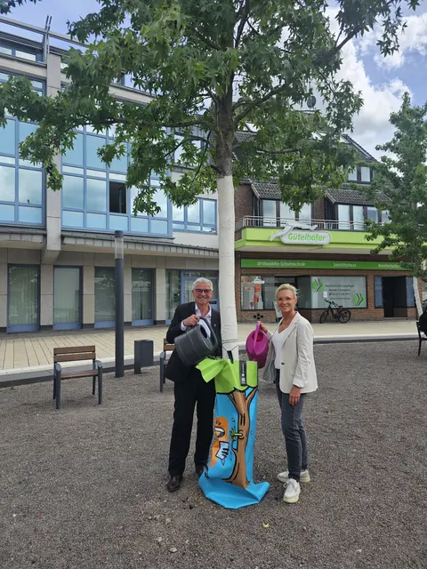 Dr. Marc Prokop und Katja Steger präsentieren einen der künstlerisch gestalteten Bewässerungssäcke der Aktion #artfortrees. Die bemalten Wassersäcke sollen Brühler Stadtbäume versorgen und zugleich Aufmerksamkeit für Klimaschutz und ehrenamtliches Engagement schaffen. | Foto: Stadt Brühl