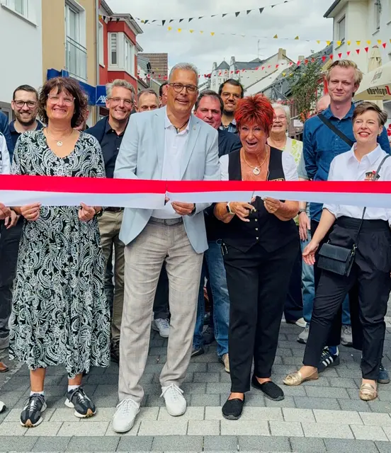 Im Beisein von Vertretern aus Politik, Verwaltung und den am Bau beteiligten Firmen gaben Bürgermeister Ulf Hürtgen und „Et fussisch Julche“ Marita Köllner die neu gestaltete Münsterstraße mit dem Durchschneiden des symbolischen Bandes nun auch offiziell frei.  | Foto: Stadt Zülpich / Torsten Beulen