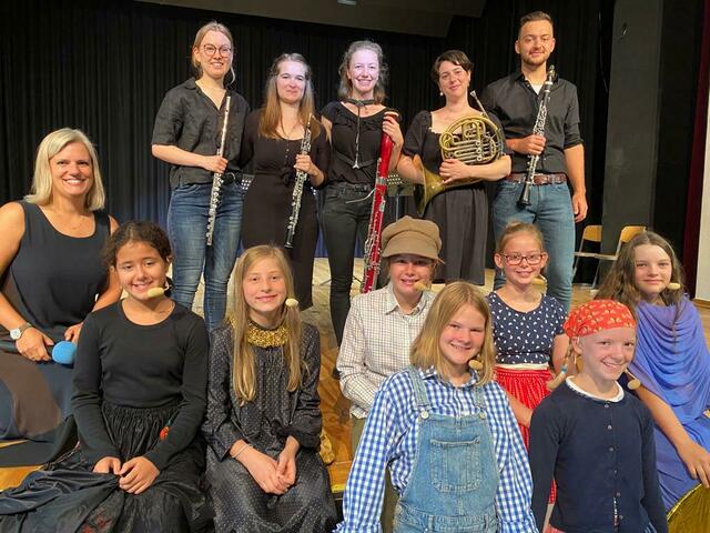 Sieben Kinder überzeugten auf der Bühne: hinten von links: Querflöte Klara Herkenhöhner, Oboe Luise Pfundstein, Fagott Katharina Zey, Horn Hilde Anders, Klarinette Philipp Epstein; Mitte: Einstudierung und Erzählerin Anke Braun; Vorne: Hexe Illiyana El Alaoui, Sandmännchen Charlotte Haas, Vater Milla Pohlscheidt, Mutter Merle Seibert, Taumännchen Mariana Kusserow; stehend vorne: Hänsel Merle Röttgen und Gretel Leonie von Unger.  | Foto: GSA