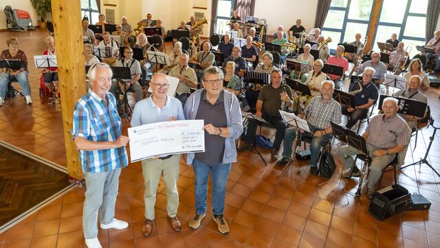 Scheckübergabe vor versammeltem Ü50-Orchester. Dirigent Peter Züll (r.) sowie Musiker und Organisator Walter Schäfer (l.) überreichten 1000 Euro an Ralf Claßen, den Vorstand der Mechernich-Stiftung.  | Foto: Ronald Larmann/pp