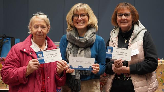 Stadtwerke-Geschäftsführerin Andrea Vogt (Mitte) überreicht Stadtgutscheine im Gesamtwert von 10.000 Euro an Tafelkoordinatorin Regina Lunetta (rechts) und Ehrenämtlerin Frau Andreé (links). Das Team der Troisdorfer Tafel verteilt diese besondere Überraschung in Weihnachts-Päckchen für Bedürftige.  | Foto: Stadtwerke