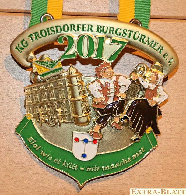 KG Troisdorfer Burgstürmer - Vereinsmitglied Hagen Krämer hat mal wieder seine Kreativität spielen lassen und diesen wunderschönen Orden in 3D-Version entworfen. Er ist in grün und gold gehalten und trägt den Schriftzug des Sessionsmottos „Ejal wie et kütt - mir maache met“. Darüber finden wir das Stadtwappen von Troisdorf sowie die Burg Wissem,  von der die Burgstürmer ihren Namen abgeleitet haben. Auch das Wahrzeichen der KG - die tanzenden Burgstürmer sowie die Kappe in gelb-grün gehalten - durften auf diesem Orden nicht fehlen. | Foto: Repro Verlag