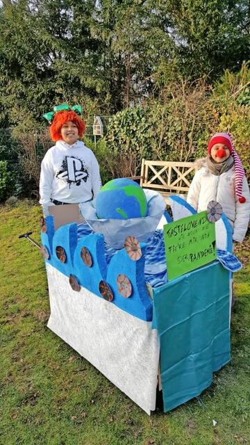 Kennziffer 16 - Anna (8) und Jannis (10) Crump aus Bergisch Gladbach haben einen Wagen gebaut, auf dem die Erde zu sehen ist, die in einer FFP2-Maske auf den Corona-Wellen schwimmt. Viren auf den Wellen verweisen auf die Pandemie.  | Foto: Familie Crump