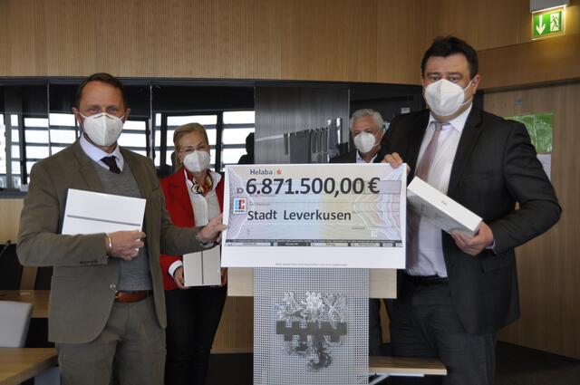 Staatssekretär Mathias Richter (vorne rechts) übergibt Oberbürgermeister Uwe Richrath (vorne links) den Scheck über 6.871.500 Euro, darüber freuen sich auch Carolin Maus und Marc Adomat (im Bildhintergrund). | Foto: Stadt Leverkusen
