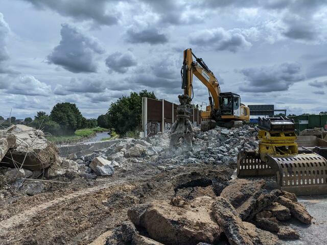 Der zerstörte Asphalt und die Teile der Lärmschutzwand werden an der A1 im Dreieck Erfttal derzeit zerkleinert und abtransportiert. | Foto: Die Autobahn GmbH Rheinland