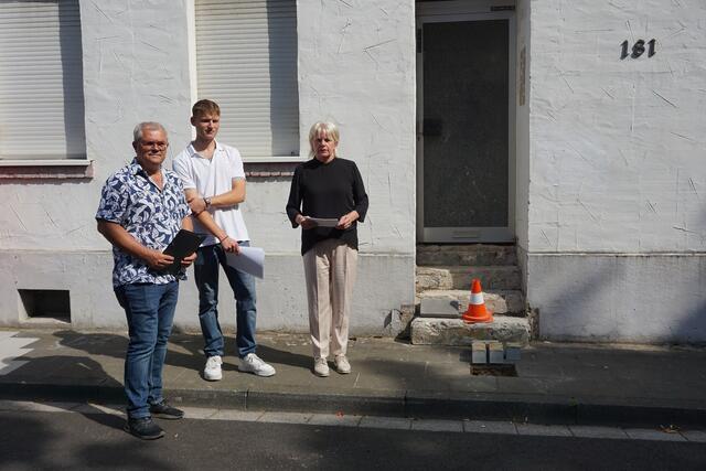 Ortsbürgermeister Edwin Schlachter, Johannes von der Gesamtschule Bergheim und die stellvertretende Bergheimer Bürgermeisterin Elisabeth Hülsewig erinnern an die Familie Simons, die im Haus Nr. 181 an der Köln-Aachener Str. in Quadrath-Ichendorf lebte.  | Foto: Andrea Floß