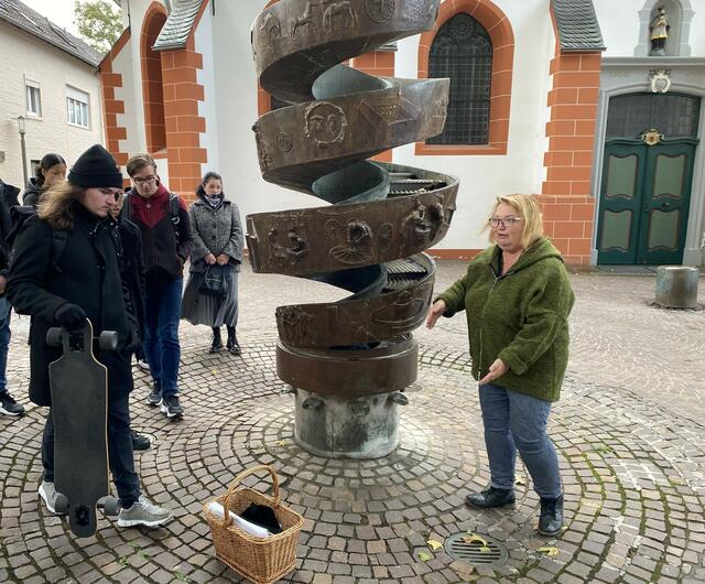 Am Historienbrunnen wird die Bergheimer Geschichte sichtbar, wie Gästeführerin Astrid Machuj den Schülerinnen und Schülern erklärte.  | Foto: Andrea Floß