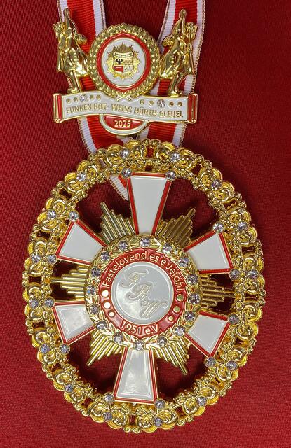 Funken Rot Weiss Hürth-Gleuel 1951 e.V.
Prunkvoll und reichlich mit Glitzer verziert ist der Orden ein wahres Schmuckstück, das traditionell auch wibbelstätzende Gardisten zeigt. Der obere Teil kann separat als Spange getragen werden. Eine kleinere Version des Ordens für zartere Hälse besteht ebenfalls. | Foto: Martina Thiele-Effertz