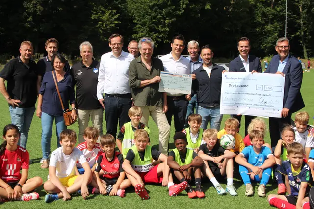 Klaus Orth von der Bethe-Stiftung (7.v.l.) sowie Holger Schwarz und Christian Walter von der Bensberger Bank (r.) überreichten auf dem Sportplatz am Heuweg die symbolischen Spendenschecks an den SV Refrath/ Frankenforst. Foto: Flick 