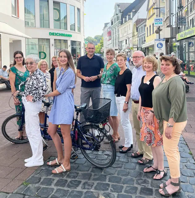 Das Tandem steht symbolisch für den Besuchsdienst: vorn vor dem Tandem: Mia Trapp (l.) und Projektleiterin Sophie Schmitz; hintere Reihe von links: Birgit Binte-Wingen (Freiwilligen-Agentur), Petra Krybus (Sozialamt), Maria Neuschaefer-Rube (Integrationsagentur), Siegburgs Bürgermeister Stefan Rosemann, Andrea Eisele (Erwachsenenbildung), Helga Roland und Ulrich Klink (ehem. Evangelischer Verein für Altenhilfe), Superintendentin Almut van Niekerk und Dagmar Redlin (Seniorenbeauftragte der Stadt Siegburg).  | Foto: EKASuR/Anna Neumann