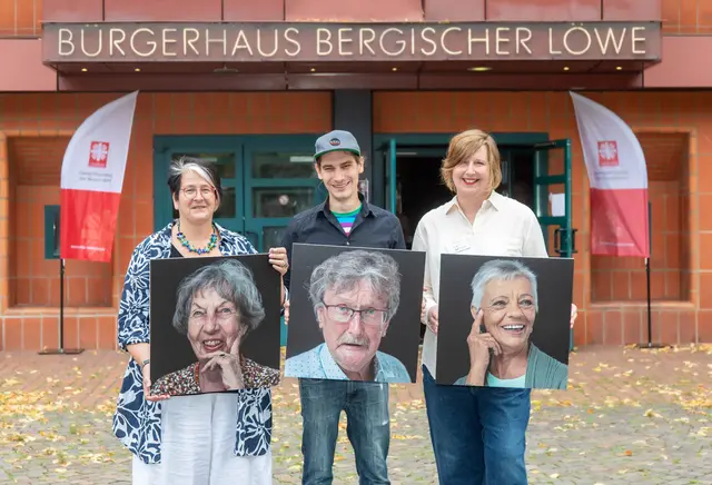 Caritas-Vorständin Raphaela Hänsch (l.) und Fachdienstleiterin Martina Schültingkemper (r.) und der Fotograf Johannes Bichmann zeigen drei Porträtfotografien der Wanderausstellung. Foto: Axel König