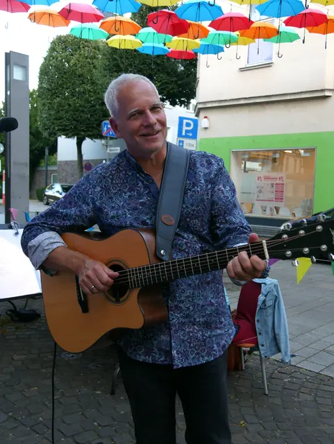 Liedermacher Marco Wrobel mit seiner Gitarre unter dem Schirmhimmel der Bahnhofstraße.  | Foto: Anita Brandtstäter