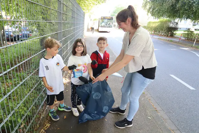 Japono, Ela und Adem finden Chipstüten, Durstlöscher und Zigarettenstummeln zu Hauf vor ihrer Schule in der Scharnhorststraße. Lehrerin Alexandra Keller unterstützt die Sammelaktion der Kinder.  Foto: NaturGut Ophoven