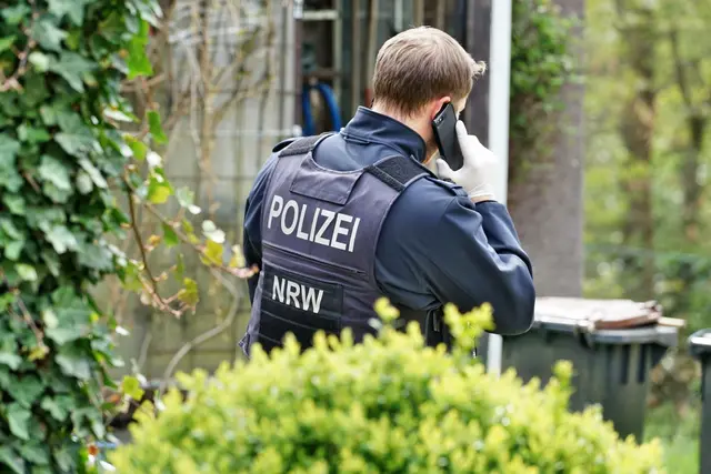 Ein Polizist telefoniert gerade am Einsatzort. Symbolbild. | Foto: hercher - stock.adobe.com