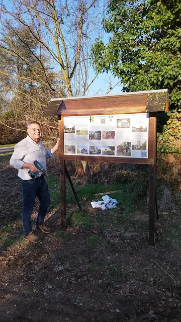 Helmut Meller vom Heimat- und Verschönerungsverein Buschhoven montiert die erneuerte Ortstafel an einem der Wanderwege rund um den Ort. Die Informationstafel wurde nach rund 20 Jahren aktualisiert und enthält nun auch QR-Codes mit weiteren Informationen. | Foto: HVV