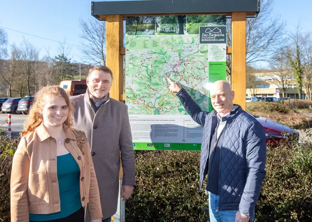 Patricia Mockenhaupt (Leiterin Tourismus- und Wirtschaftsförderung), Bürgermeister Michael Eyer und Guido Lazotta, Sprecher der Bürgerwerkstatt Tourismus, stellten die Tafel am Schulzentrum Cyriax vor. Foto: Axel König