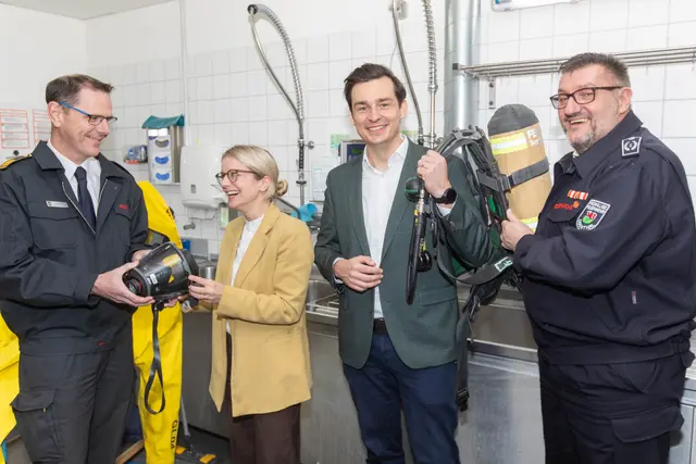 Bergisch Gladbachs Feuerwehrchef Jörg Köhler (l.) half Odenthals Bürgermeisterin Laura Lundberg bei einer Atemschutzmaske und Odenthals Wehrleiter Axel Staehler half Bergisch Gladbachs Bürgermeister Marcel Kreutz bei einer Atemluftflasche. Foto: Axel König