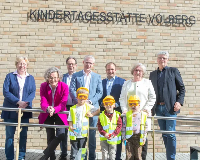 Neues Heim nach der Flut 2021 (v.l.): Presbyteriums-Vorsitzende Monika Mattern-Klosson, NRW-Bauministerin Ina Scharrenbach, Vize-Landrat Rhein-Berg Peter Lautz, Bürgermeister Yannick Steinbach, NRW-Landtagsabgeordneter Martin Lucke, Vize-Bürgermeisterin und Stadtratsmitglied Veronika Rilke-Haerst und Architekt Bernd Oxen mit Kindern der Kita Volberg. Foto: Axel König