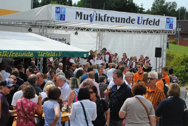 Vor der Bühne versammeln sich zahlreiche Besucherinnen und Besucher, während die Musikfreunde Urfeld und ihre Gäste das Programm gestalten. | Foto: MFU