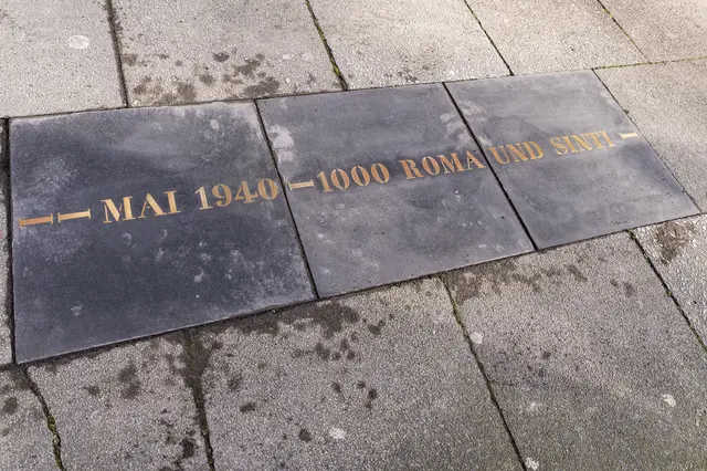 Die Messingplatte erinnert an den großen Transport von Sinti und Roma quer durch Köln vom Schwarz-Weiß Platz in Köln Ossendorf in das Messegelände in Köln Deutz am 16.Mai 1940. Von dort aus kam es fünf Tage später zur ersten Massen-Deportation nach Polen. | Foto: Alexander Roll