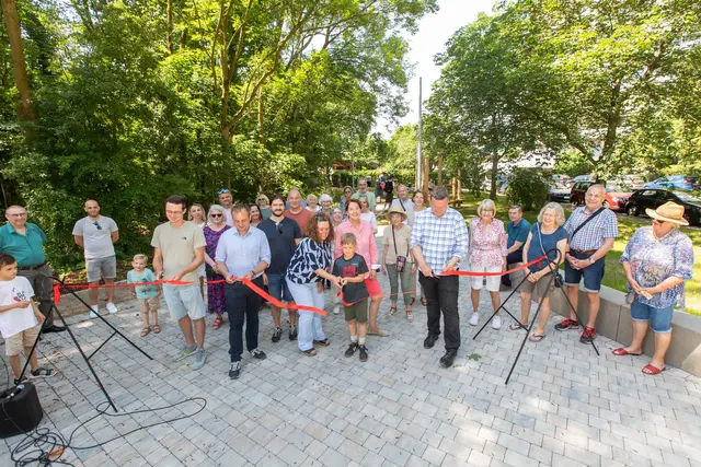 Eröffnung mit Scheren und rotem Band (v.l.): Bastian Bosbach (Techniker der Abteilung Planen und Bauen), Landtagsabgeordneter Martin Lucke, Vize-Bürgermeisterin Brigitta Opiela, ein Junge aus dem Wohnpark und Volker Oberreuther (Sachgebietsleiter Stadtgrün) eröffneten mit Bürger*innen das Areal zwischen den teils sehr hohen Häusern. Foto: Axel König