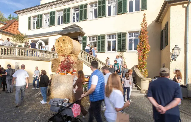Besucher*innen auf dem Herbstmarkt vor der Kulisse von Schloss Eulenbroich. Eine Strohfigur begrüßte die Gäste im Innenhof. Foto: Axel König